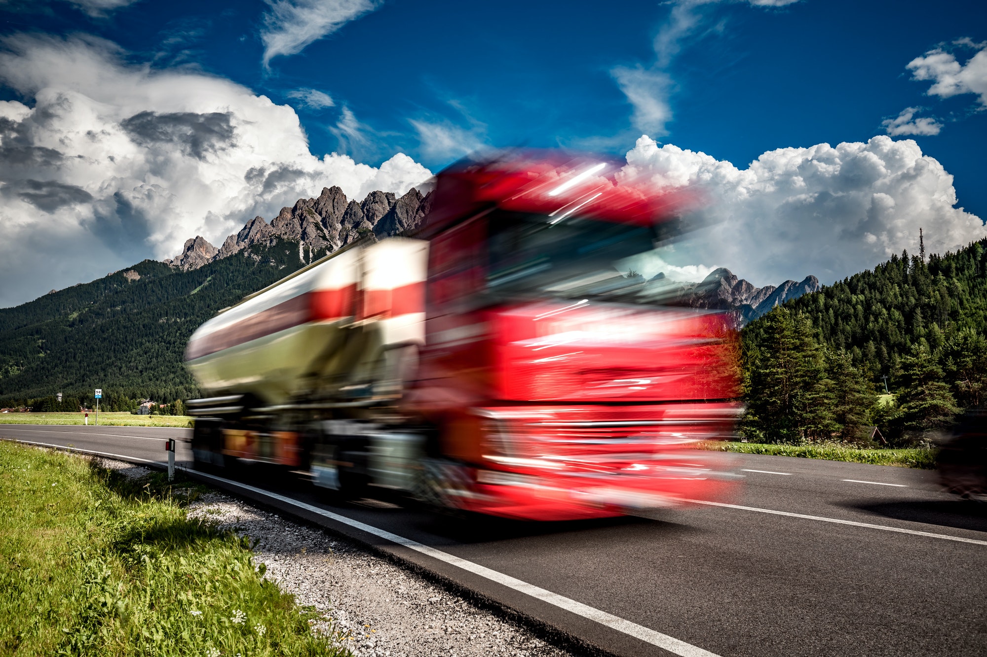 Fuel truck rushes down the highway in the background the Alps. T